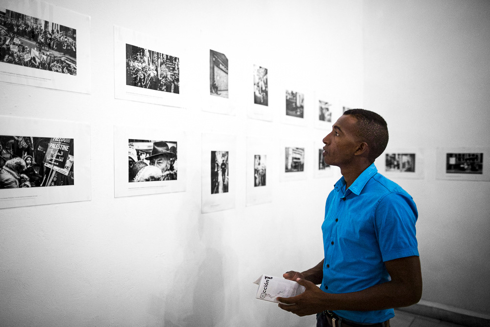 Picture of the frames on the exhibition wall with the caption and also Gallery Attendant at "londres. Detrás y debajo del palacio de buckingam" exhibition space. gallery arte soy in santiago de cuba, cuba. 2015  © Pedro Rodrigues