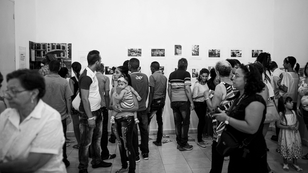 Picture of the frames on the exhibition wall with the caption and also many Gallery Attendants at "Londres. Detrás y debajo del palacio de buckingam" exhibition space. gallery arte soy in santiago de cuba, cuba. 2015  © Pedro Rodrigues
